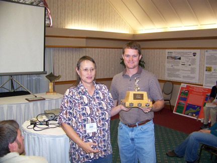 Joan Trial presents Frank Frost with the "Lunker Award" for best angling picture. A photo of his son fishing.